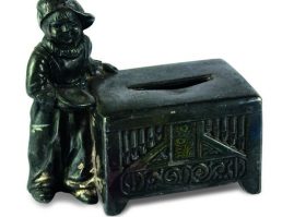 Metal piggy bank with a little boy standing next to a carved chest, from the begining of the 20th century