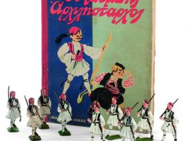 Μολυβένια ευζωνάκια της αγγλικής εταιρείας BRITAINS που κατασκευάζονταν από το 1919, με φόντο χιομοριστικό παιδικό βιβλίο του Γρηγορίου Ξενόπουλου, με τίτλο Ο Μπέμπης αρχιλήσταρχος (1932