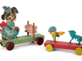 Wooden wheeled toys to be pulled by a string: Mother-bear with a baby’s cradle and a dog fighting a rooster. The toys feature a wire mechanism to achieve motion of the figures when pulled. The toys are of Greek origin and date back to the 1930s-50s