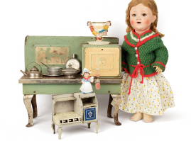 Talking doll, dating back to the Interwar period, probably German origin, placed next to two tin stoves, American and English origin, from thw 1920s-50s