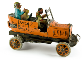 Χιουμοριστικό τσίγκινο, λιθόγραφο κουρδιστό αυτοκίνητο με τρεις φιγούρες για επιβάτες. Παιχνίδι γνωστό ως «Amos ‘n’ Andy», της αμερικάνικης εταιρείας «Marx», της δεκαετίας του 1950